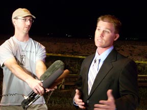 Ari Armstrong holding mics as TV crews interview Trevor Materasso.