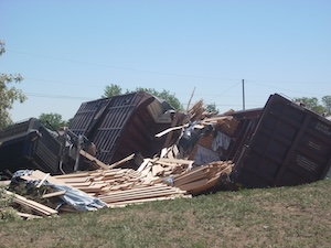 Derailed train car with lumber scattered across the ground.