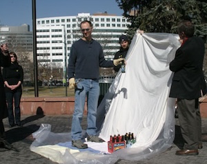 Ari Armstrong prepares to smash a beer bottle in front of a plastic lined sheet.