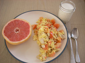 Scrambled eggs with tomato, half a grapefruit, and a cup of milk.
