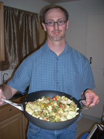 The author holding a large pan of food with vegetables, quinoa, and olive oil.
