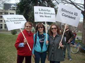 Three women hold signs reading Don't Mortgage My Grandchildren's Future, Liberty All the Stimulus We Need, and Silence is Consent.