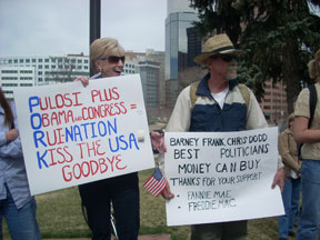 A woman holds a sign reading Pulosi Plus Obama and Congress equals Ruenation Kiss the USA Goodbye, typos in original, and a man holds a sign reading Barney Frank Chris Dodd Best Politicians Money Can Buy.