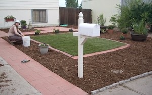 Jennifer Armstrong works in a yard with red pavers and mulch surrounding grass