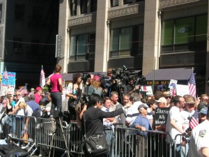 A crowd gathers outside behind a temporary fence.