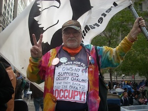 A man with a Vietnam Veterans cap wears a sign reading OWS NY supports Occupy Oakland give them back and keep the park, occupy..