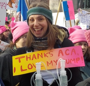 A woman holds a sign reading thanks ACA I love my pump.