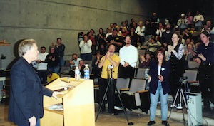 Masters, standing in front of a crowd, which is giving a standing ovation.