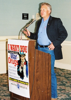 Masters at a lectern with a sign reading I Want you to Help End the War on Drugs.