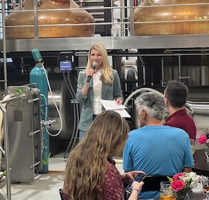 Brittany Pettersen speaking at a YIMBY Denver event held in a distillery in Arvada.